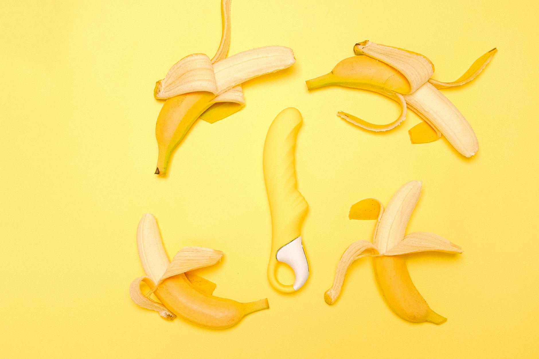 Bright yellow lemon vibrator surrounded by fresh lemons on a yellow background, symbolizing renewal and sensuality