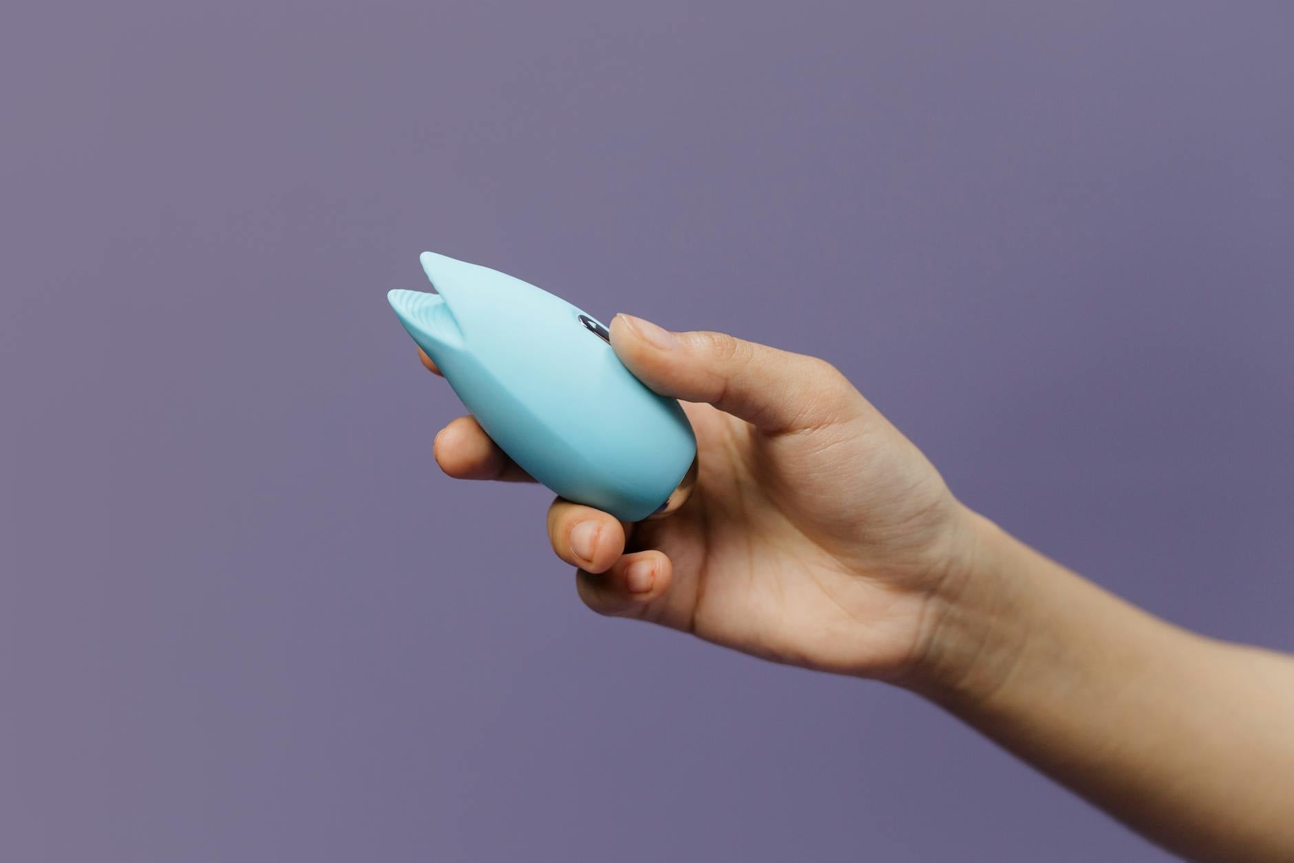 Hands holding colorful lemon clitoral vibrators and intimate wellness toys